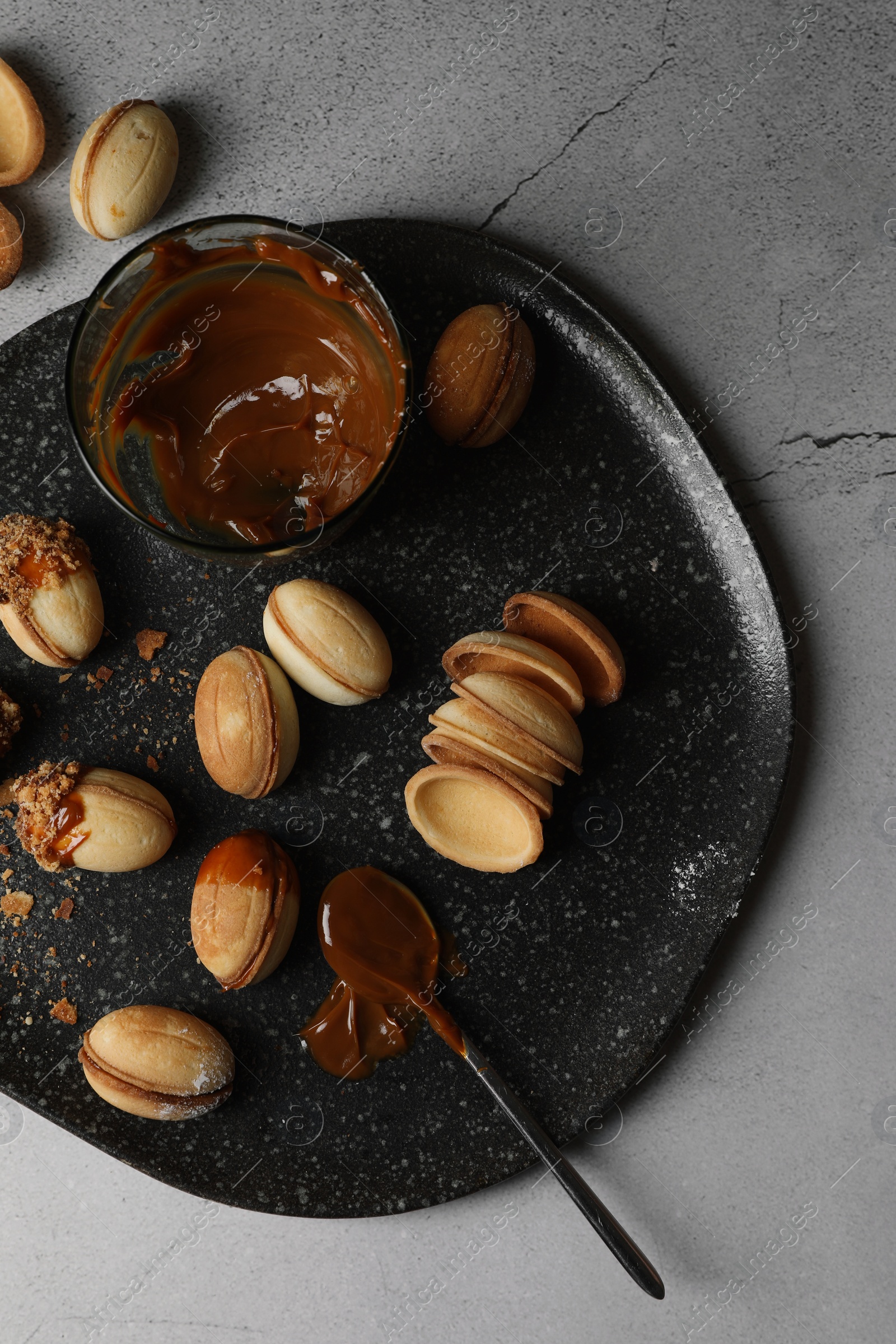 Photo of Delicious walnut shaped cookies with condensed milk on grey table, flat lay