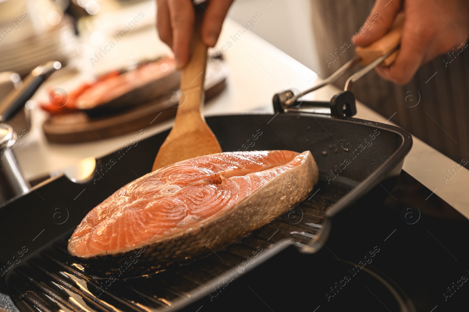 Photo of Man cooking fresh salmon steak in frying pan, closeup