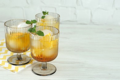 Photo of Delicious cocktails with orange, mint and ice balls on white wooden table, space for text