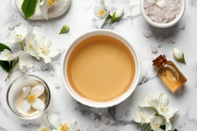 Flat lay composition with jasmine essential oil and fresh flowers on white marble table