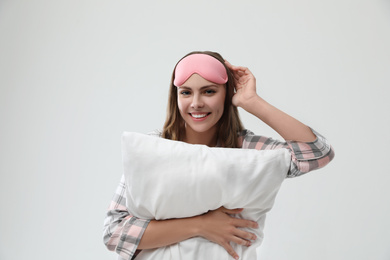 Beautiful woman with pillow on light grey background. Bedtime