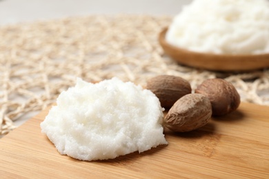 Shea butter and nuts on wooden board, closeup