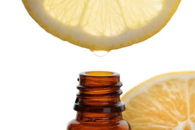 Photo of Dripping lemon essential oil from into bottle isolated on white