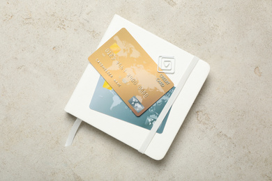 Notebook and credit cards on light background, top view