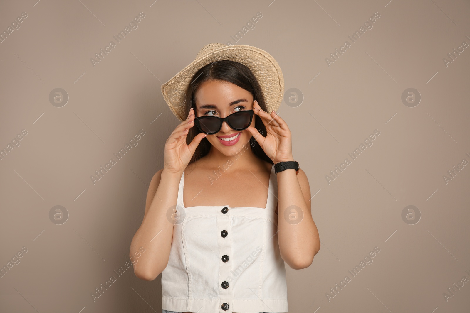Photo of Beautiful young woman with straw hat and sunglasses on beige background. Stylish headdress
