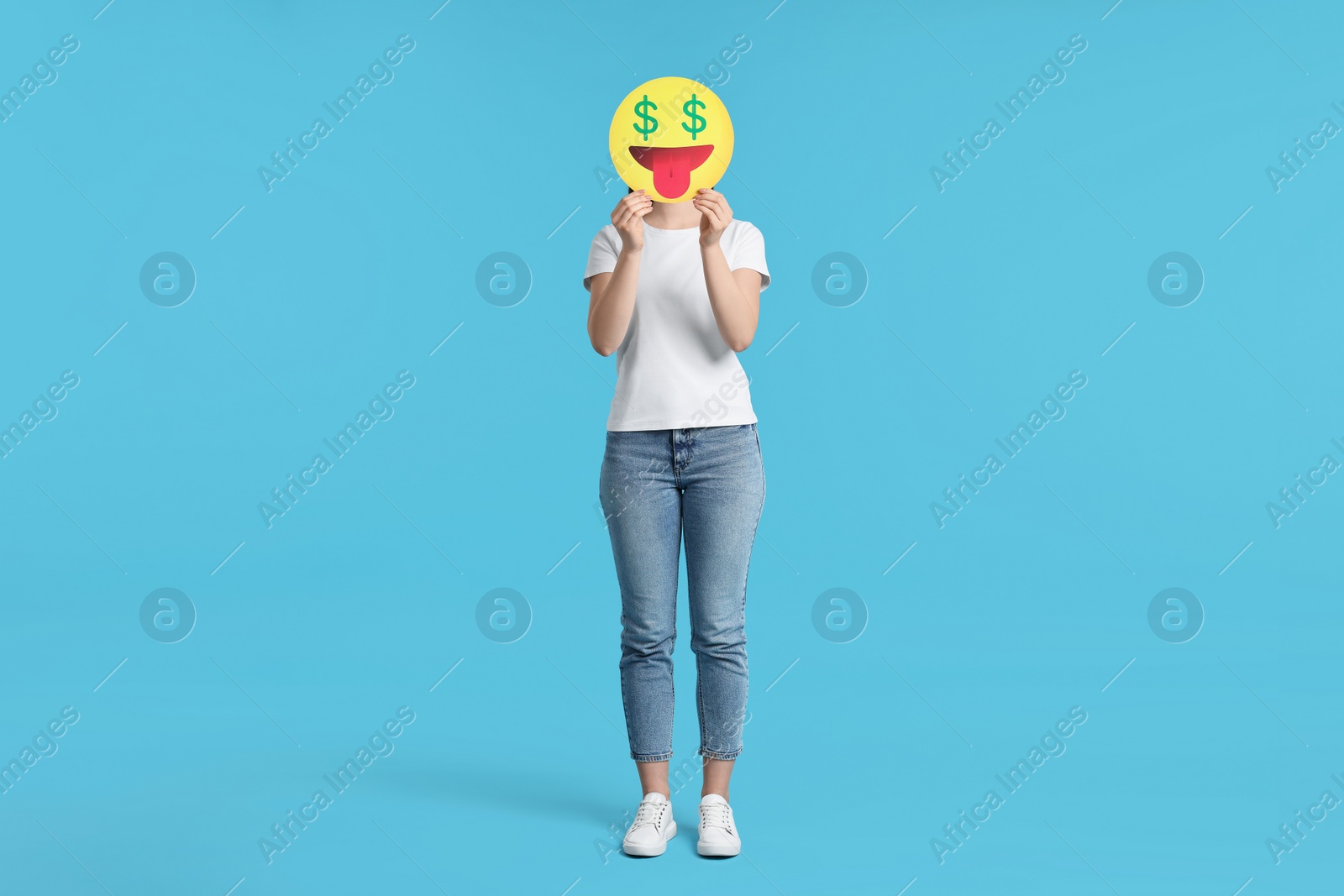 Photo of Woman covering face with dollar signs instead of eyes on light blue background