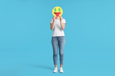 Woman covering face with dollar signs instead of eyes on light blue background