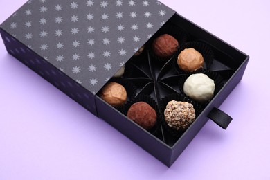 Box of tasty chocolate candies on violet background