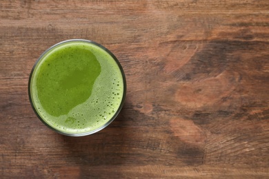 Glass with delicious detox juice on wooden background, top view