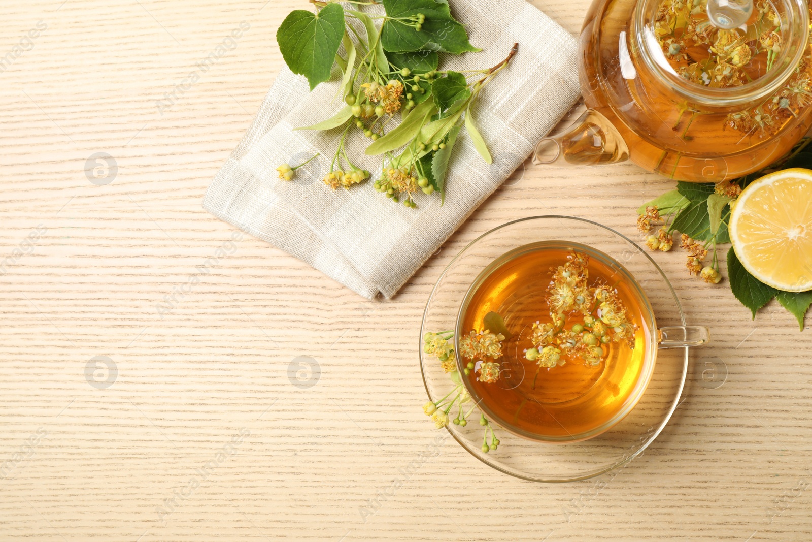 Photo of Flat lay composition with tasty tea and linden blossom on wooden table. Space for text