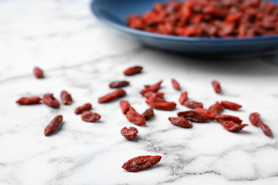 Photo of Dried goji berries on white marble table, closeup