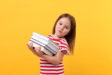 Photo of Cute little girl with books against orange background