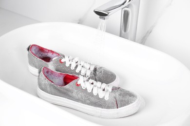 Washing pair of sport shoes in sink