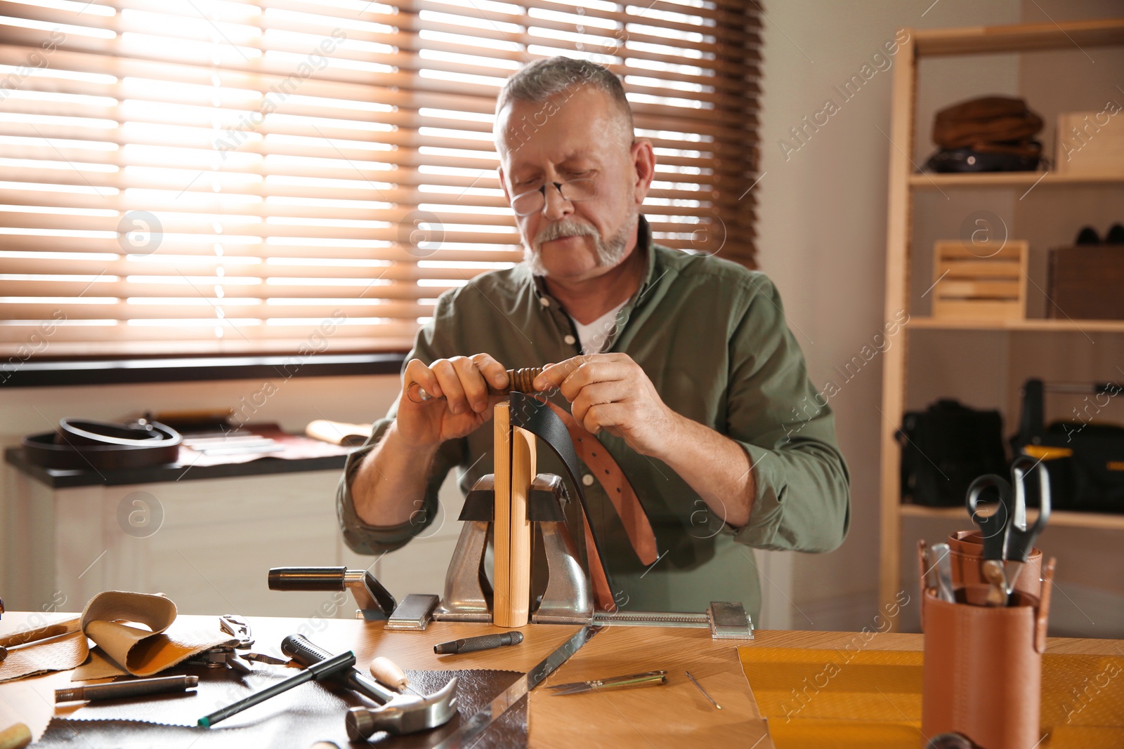 Photo of Man burnishing edges of leather belt in workshop