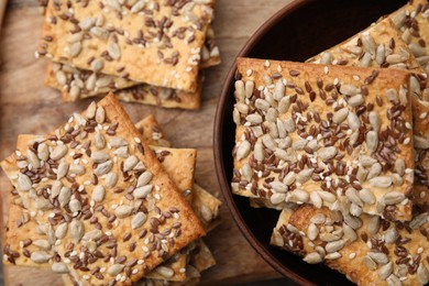 Cereal crackers with flax, sunflower and sesame seeds on wooden table, top view