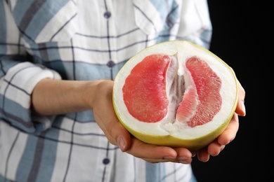 Photo of Woman holding half of fresh red pomelo on black background, closeup