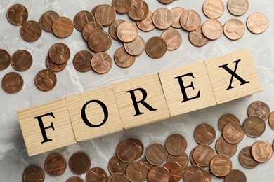 Photo of Word Forex made with wooden cubes and coins on white marble table, flat lay
