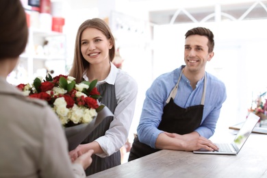 Young florists with customer in flower shop