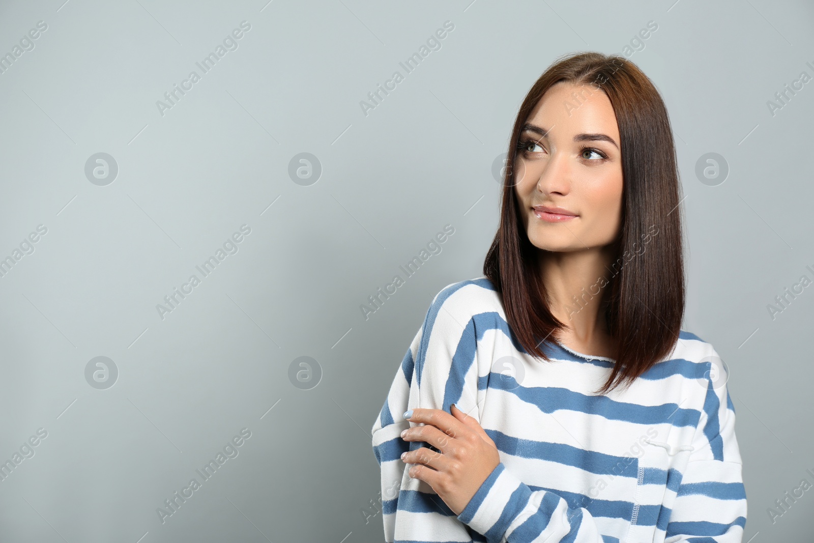 Photo of Portrait of pretty young woman with gorgeous chestnut hair on light grey background, space for text