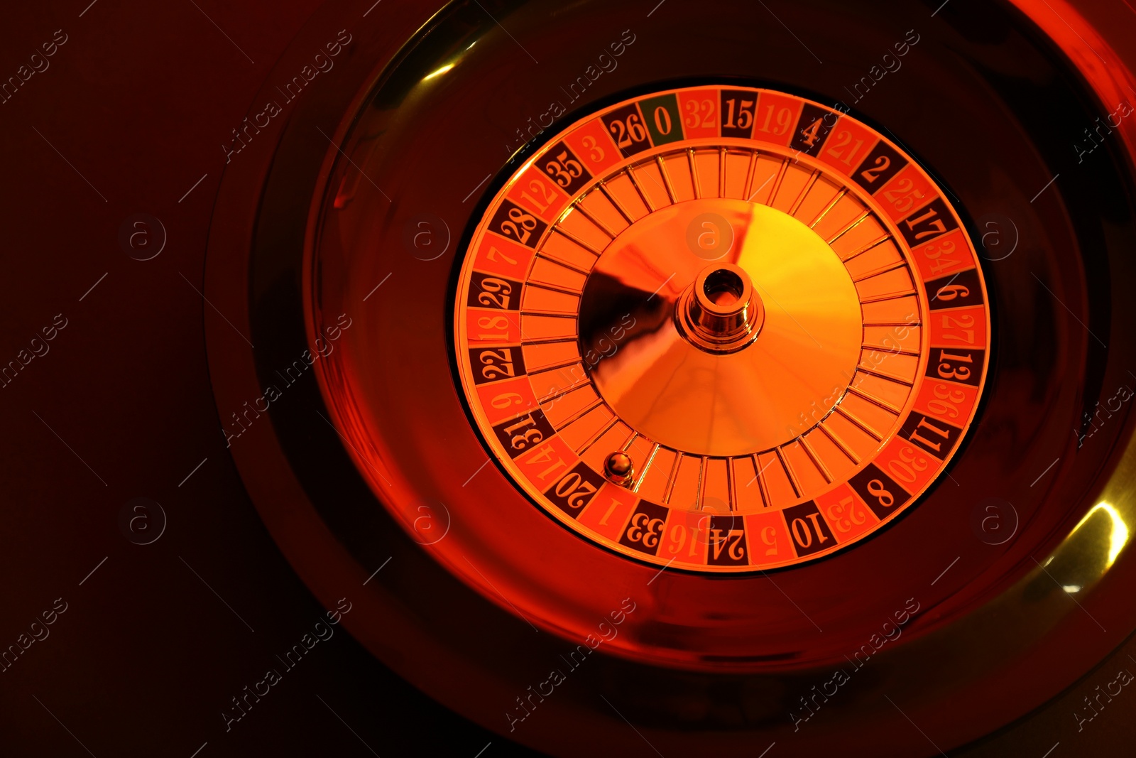 Photo of Roulette wheel with ball on dark background, above view. Casino game