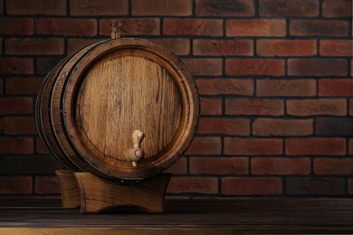 Wooden barrel with tap on table near brick wall, space for text