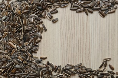 Frame of sunflower seeds on wooden table, flat lay. Space for text