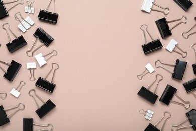 Photo of Black binder clips on beige background, flat lay. Space for text