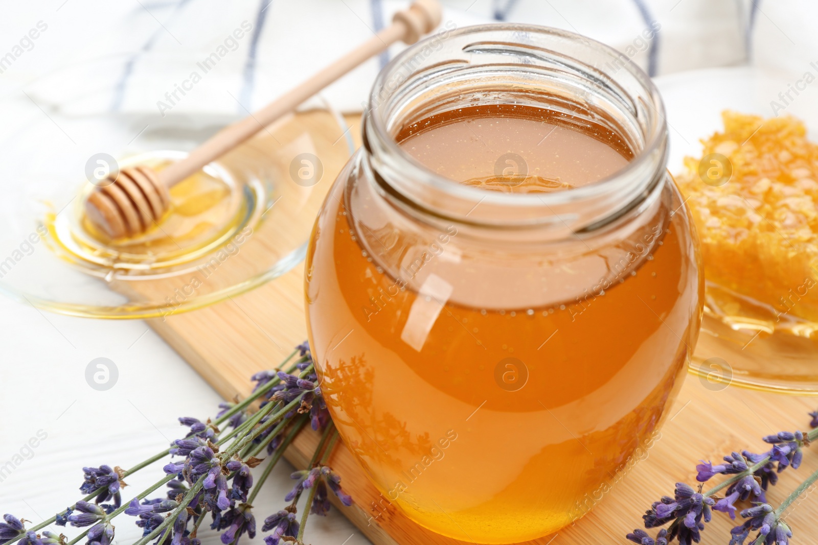 Photo of Tasty honey and lavender flowers on wooden board, closeup