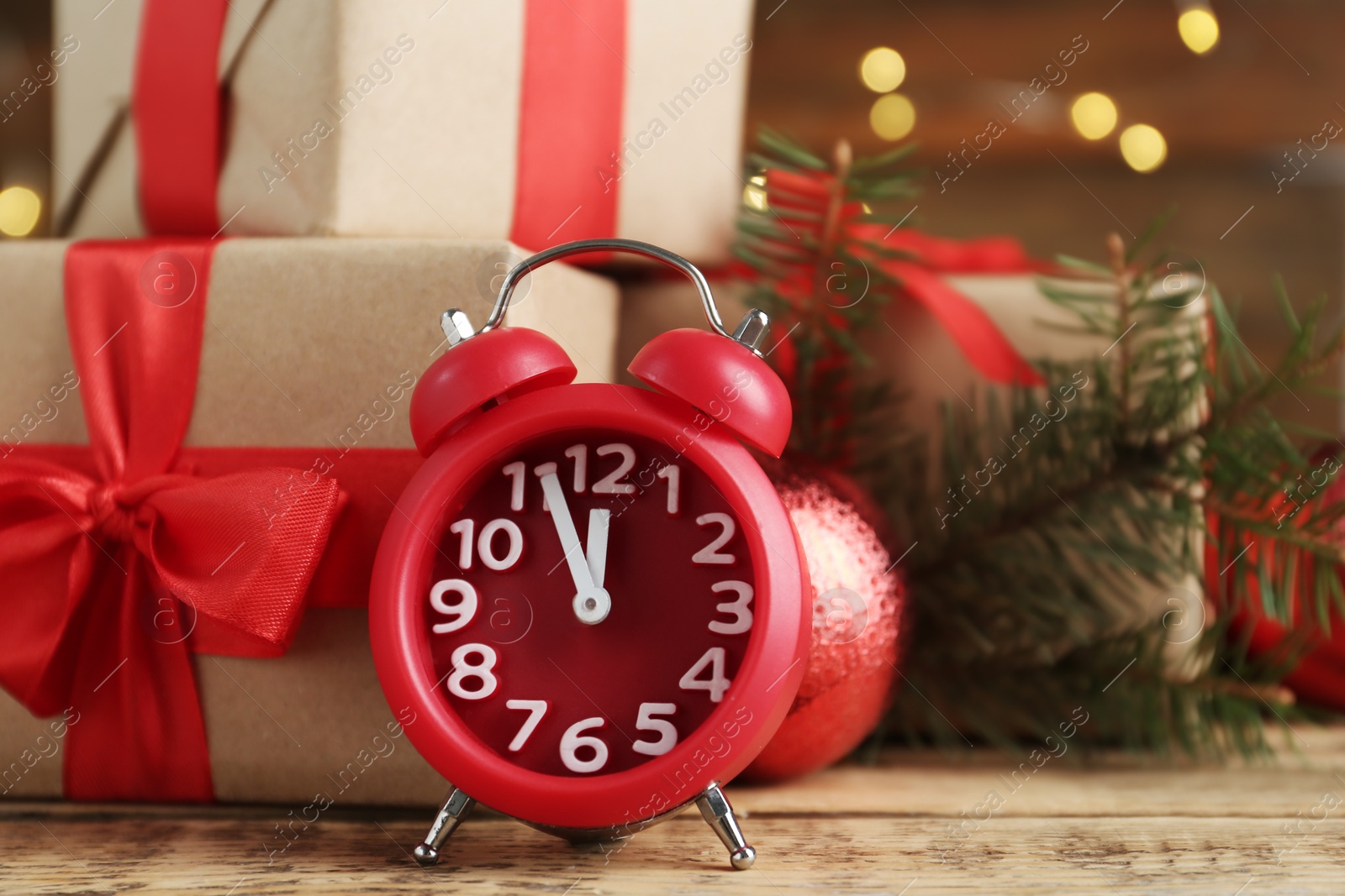 Photo of Beautiful composition with alarm clock and Christmas gifts on wooden table, closeup. Boxing day
