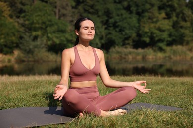 Beautiful woman practicing yoga on mat outdoors. Lotus pose