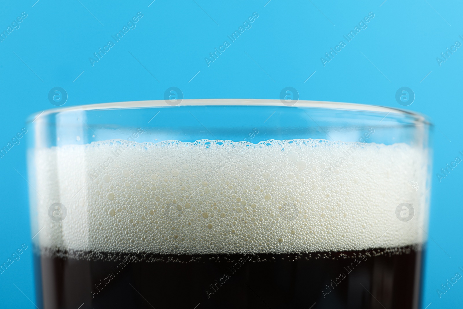 Photo of Delicious homemade kvass in glass on light blue background, closeup