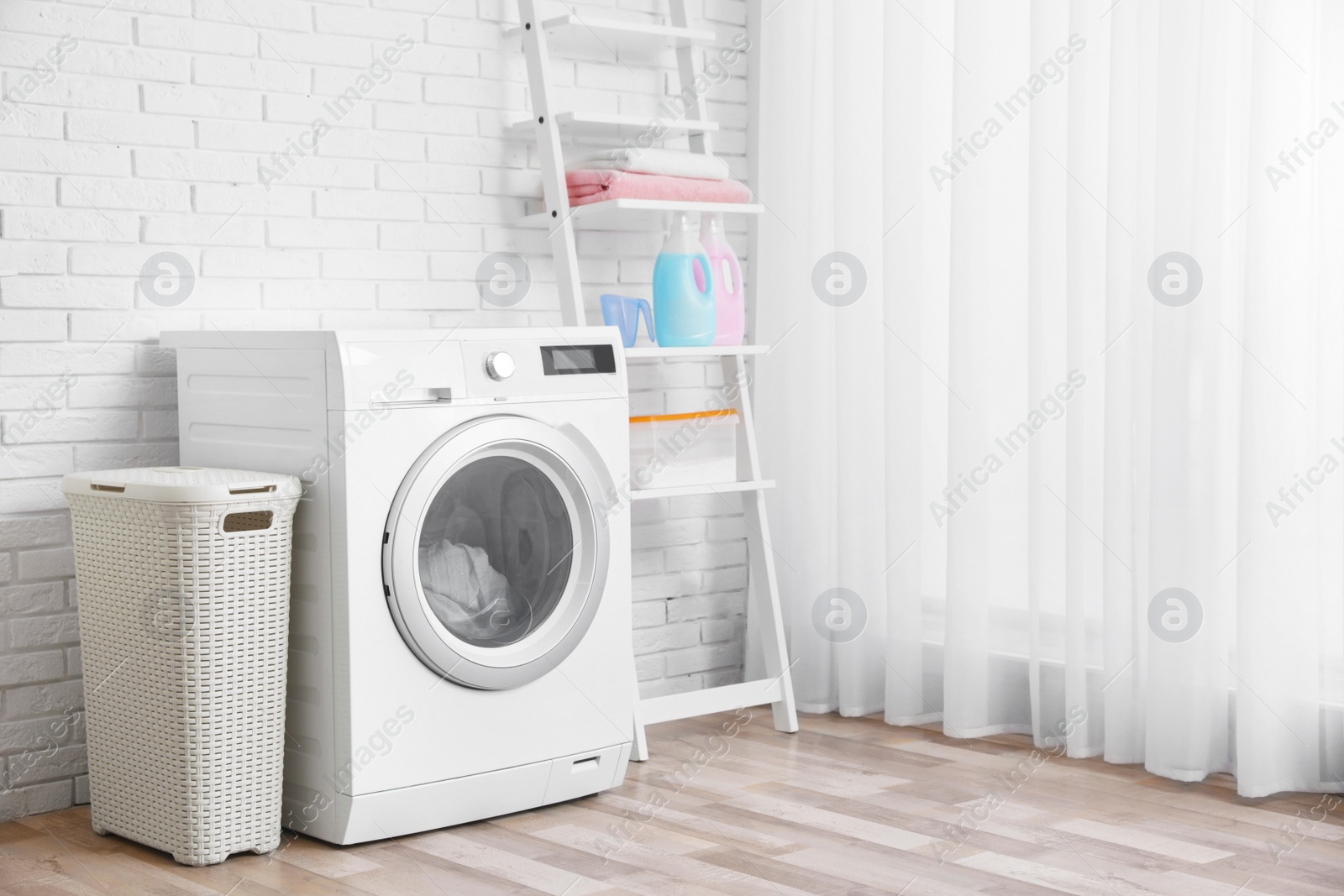 Photo of Modern washing machine near brick wall in laundry room interior, space for text