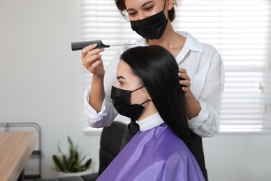 Photo of Professional stylist working with client in salon. Hairdressing services during Coronavirus quarantine