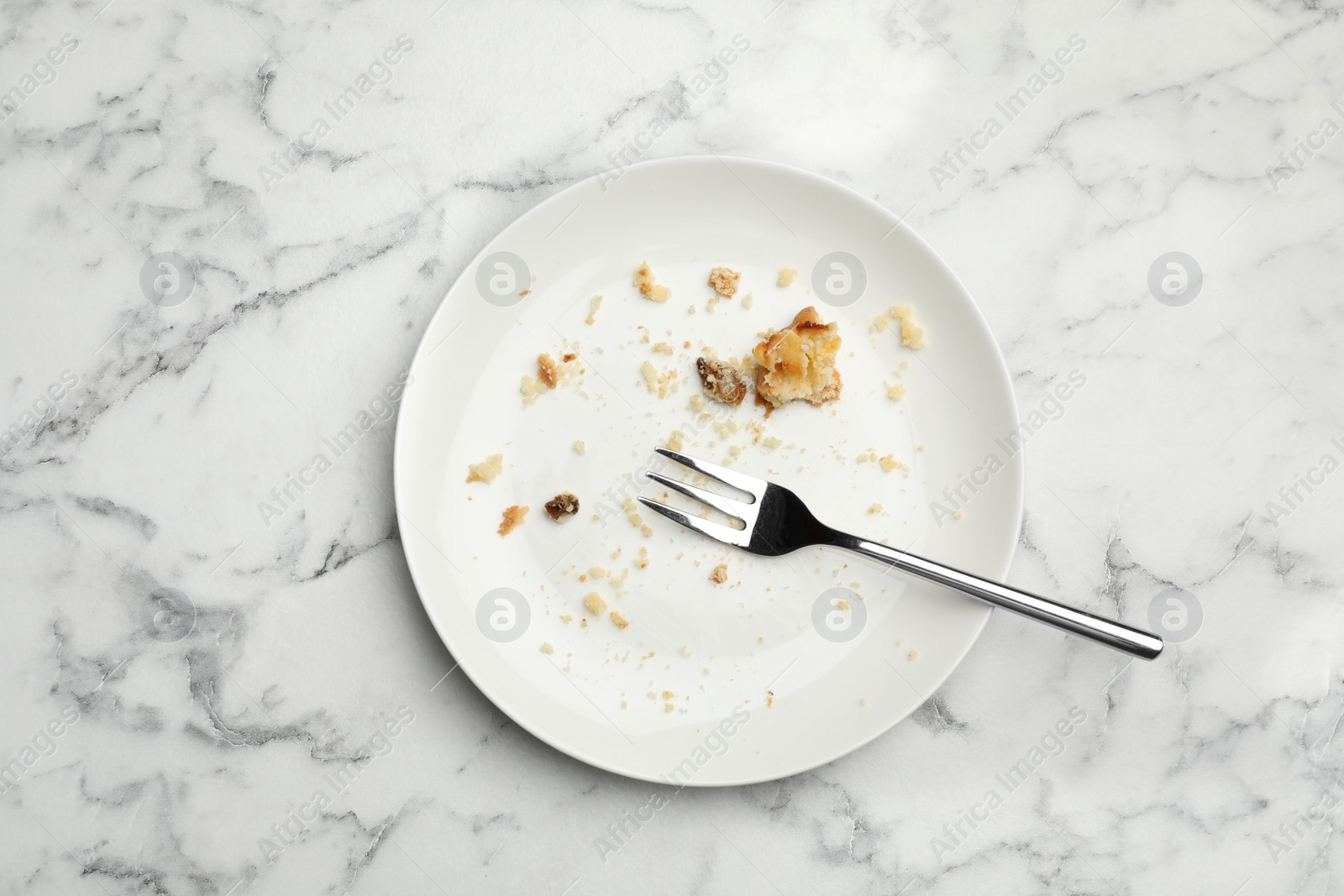 Photo of Dirty plate with food leftovers and fork on marble background, top view