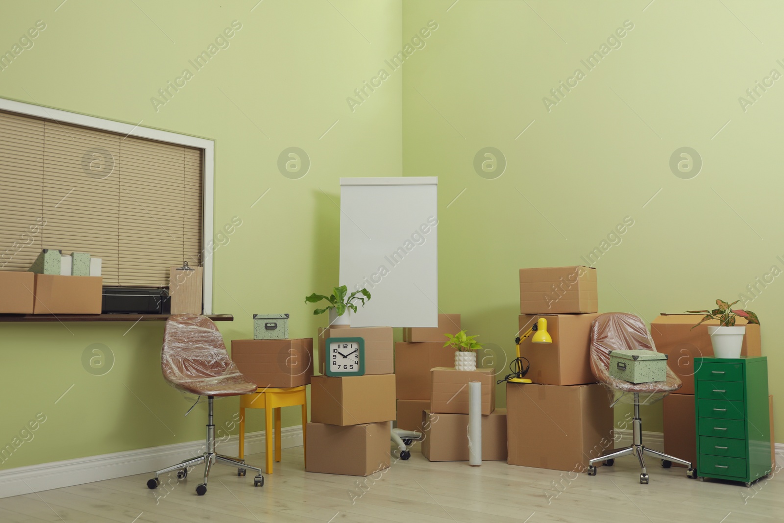 Photo of Cardboard boxes with packed stuff in new office. Moving day