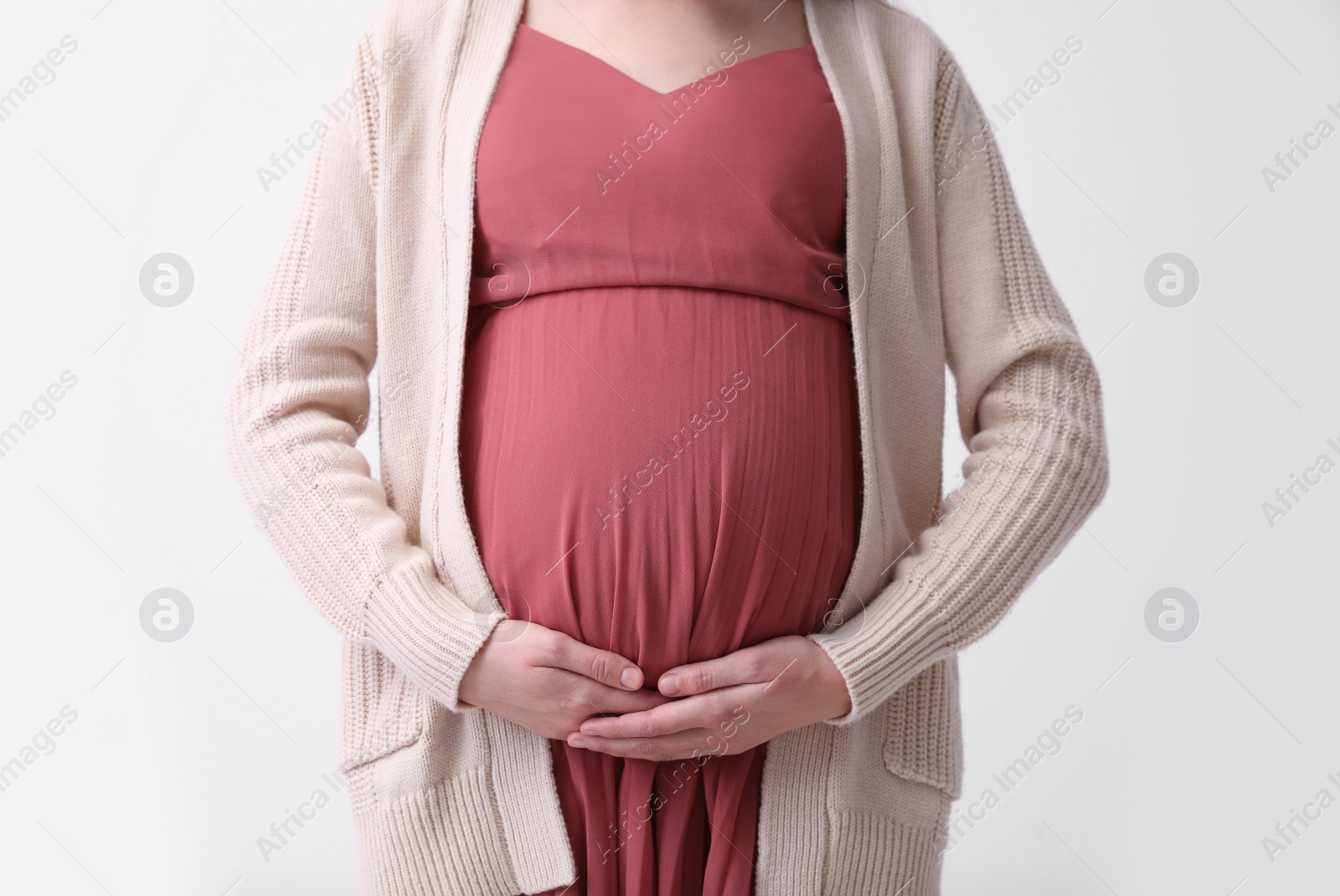 Photo of Young pregnant woman on light background, closeup