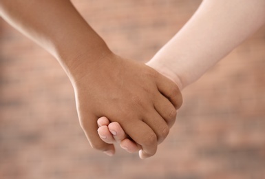 Photo of Children holding hands on blurred background, closeup. Unity concept