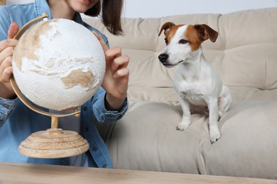 Woman with globe near dog indoors, closeup. Travel with pet concept