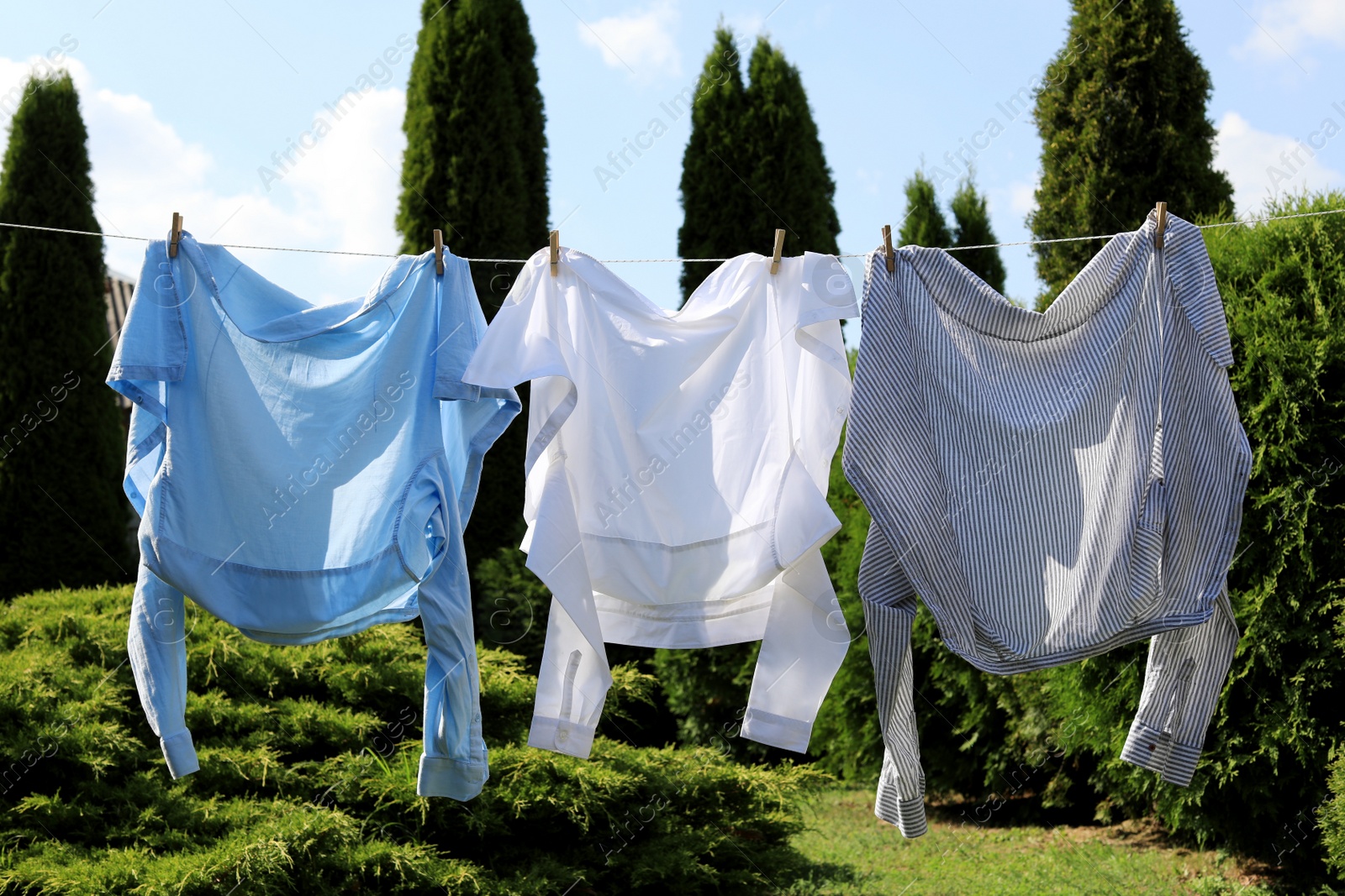 Photo of Clean clothes hanging on washing line in garden. Drying laundry