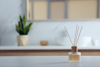 Photo of Aromatic reed air freshener on table indoors. Space for text