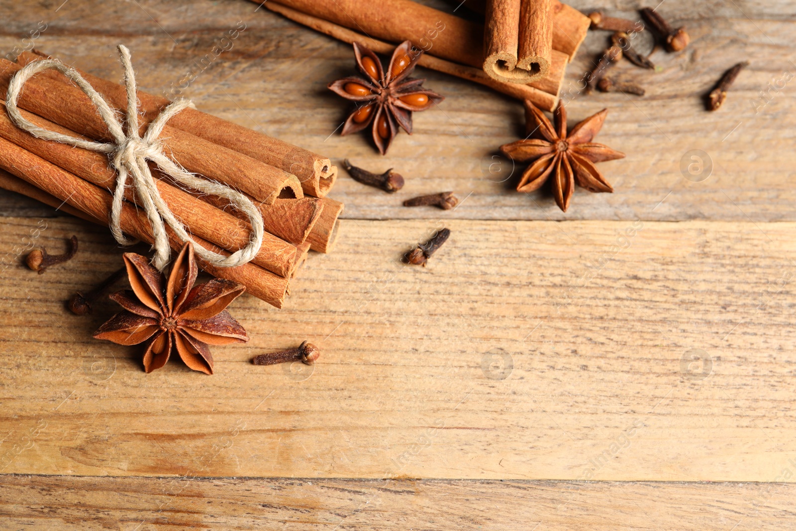 Photo of Different aromatic spices on wooden table, flat lay. Space for text