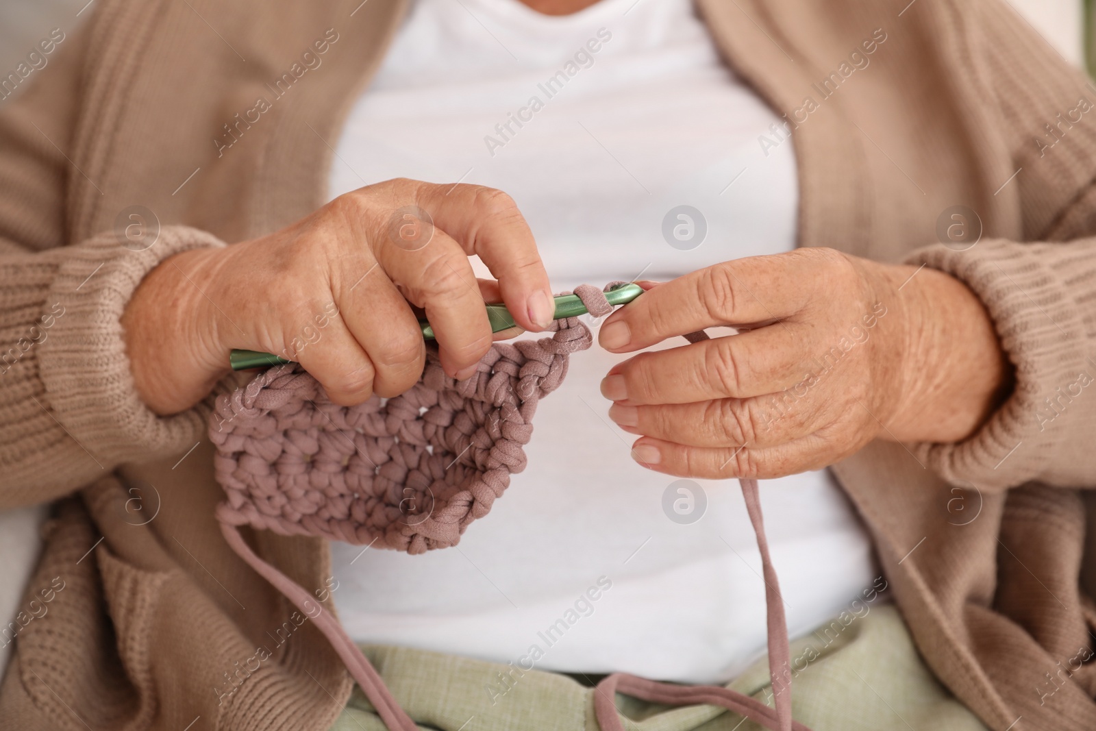 Photo of Elderly woman crocheting at home, closeup. Creative hobby