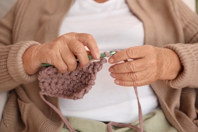 Photo of Elderly woman crocheting at home, closeup. Creative hobby