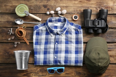 Photo of Flat lay composition with shirt and camping equipment on wooden background