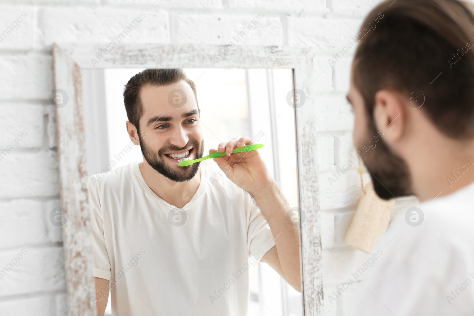 Photo of Young man brushing his teeth in bathroom