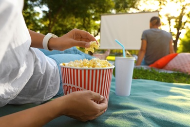 Photo of Woman with popcorn watching movie in open air cinema, closeup. Space for text