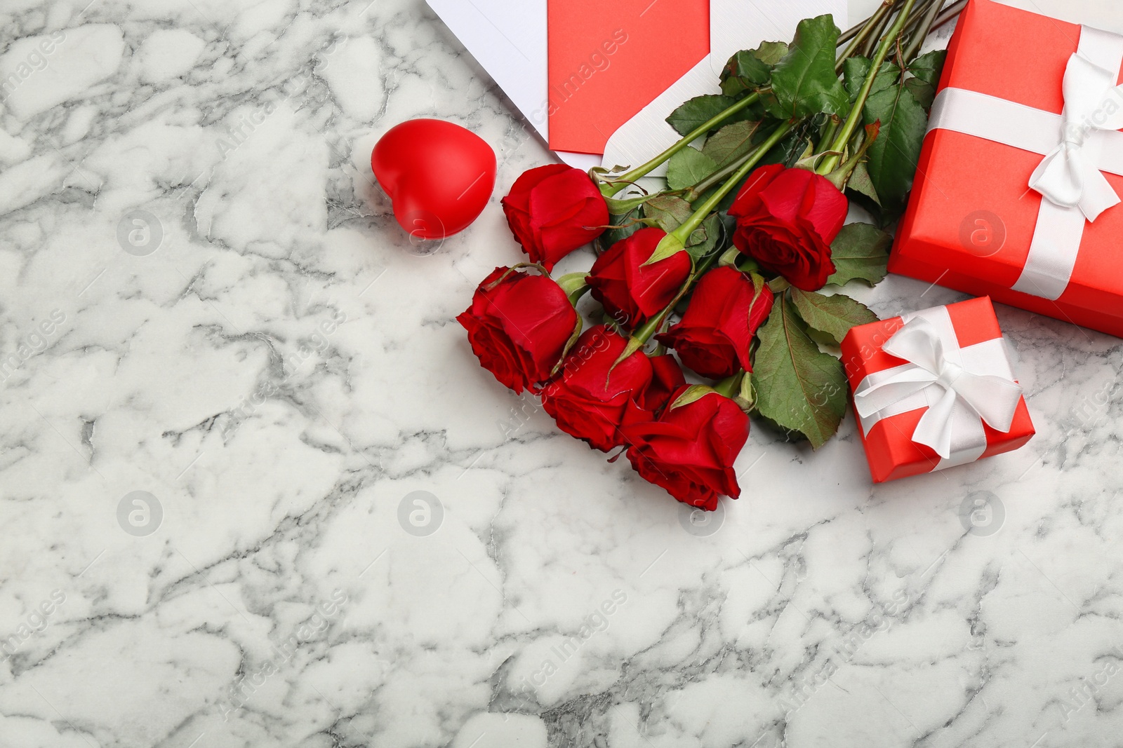 Photo of Flat lay composition with beautiful red roses and gift boxes on white marble background, space for text. Valentine's Day celebration