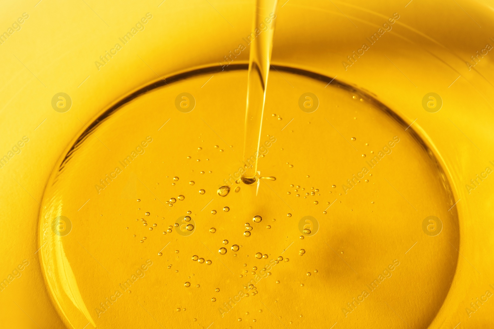 Photo of Pouring cooking oil into glass bowl, closeup