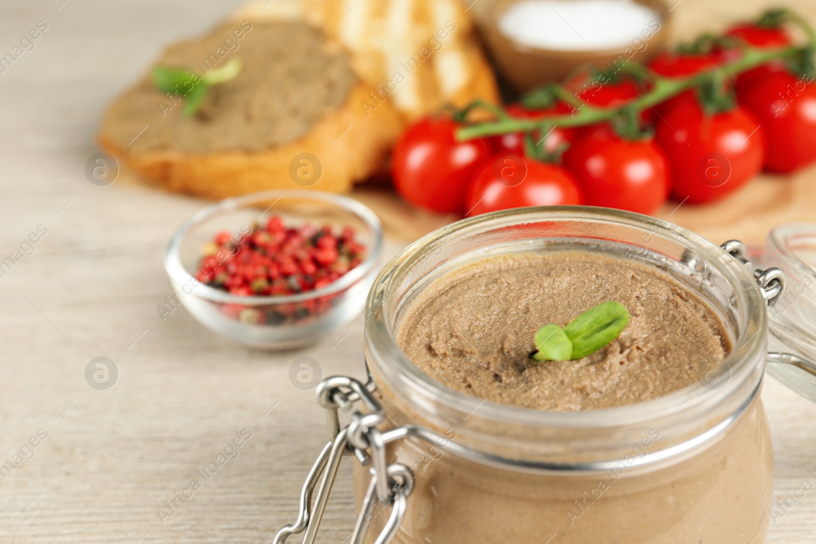 Photo of Glass jar with delicious liver pate on table, closeup. Space for text