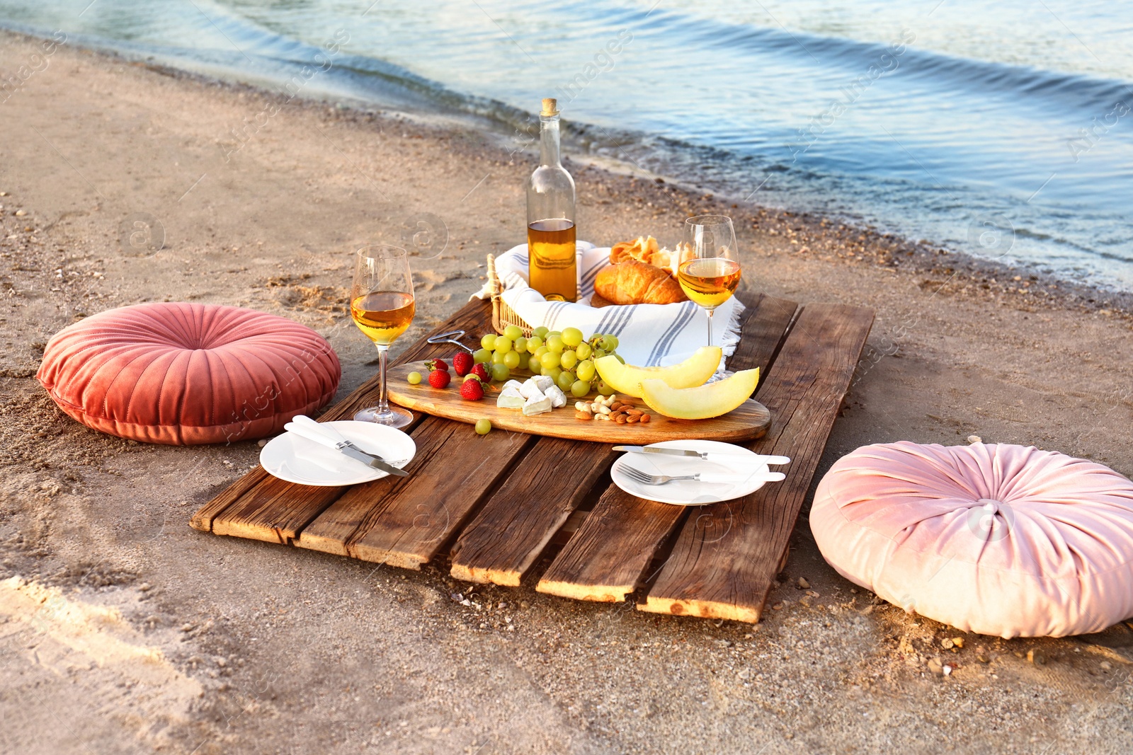 Photo of Food for picnic and white wine served on wooden pallet near river